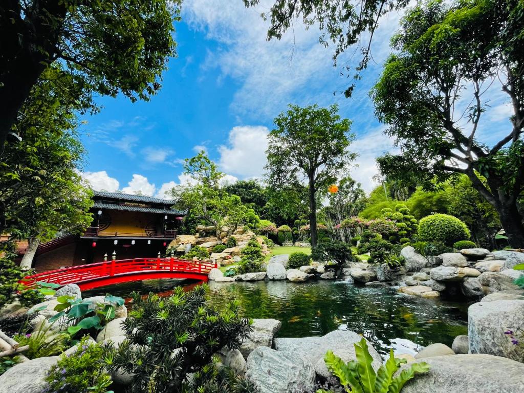 un puente rojo sobre un río en un jardín en Phuong Nam Resort, en Thuan An