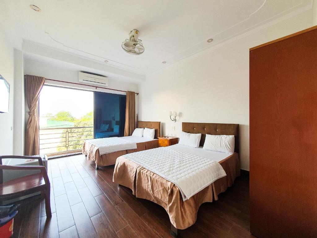a hotel room with two beds and a large window at Van Thanh Hotel Cua Lo in Cửa Lò