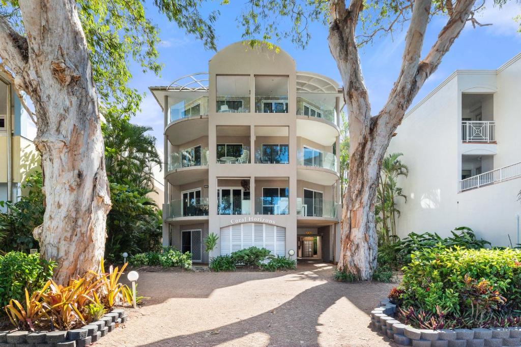 an apartment building with trees in front of it at Coral Horizons - Beachfront apartments in Palm Cove