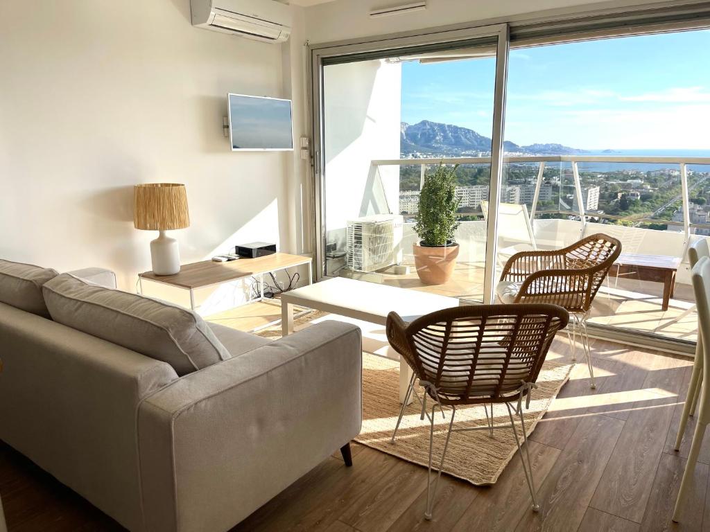 a living room with a couch and chairs and a balcony at Studio vue mer exceptionnelle proche métro et bus in Marseille
