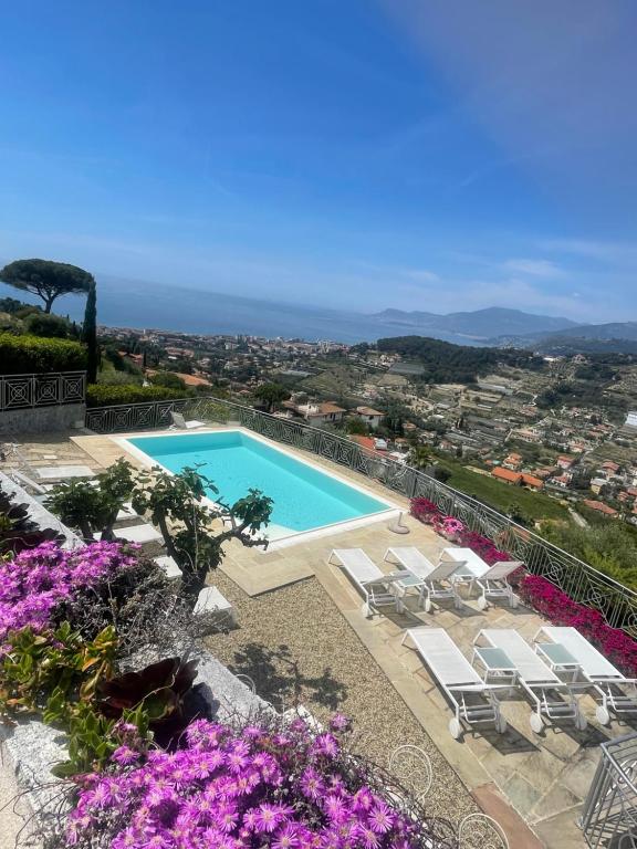 uma vista para uma piscina com cadeiras e flores em Villa Gaia - Luxury Villa, pool & wellness rooms em Bordighera