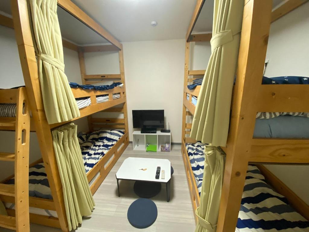 a room with four bunk beds and a desk at パインツリー in Matsuyama