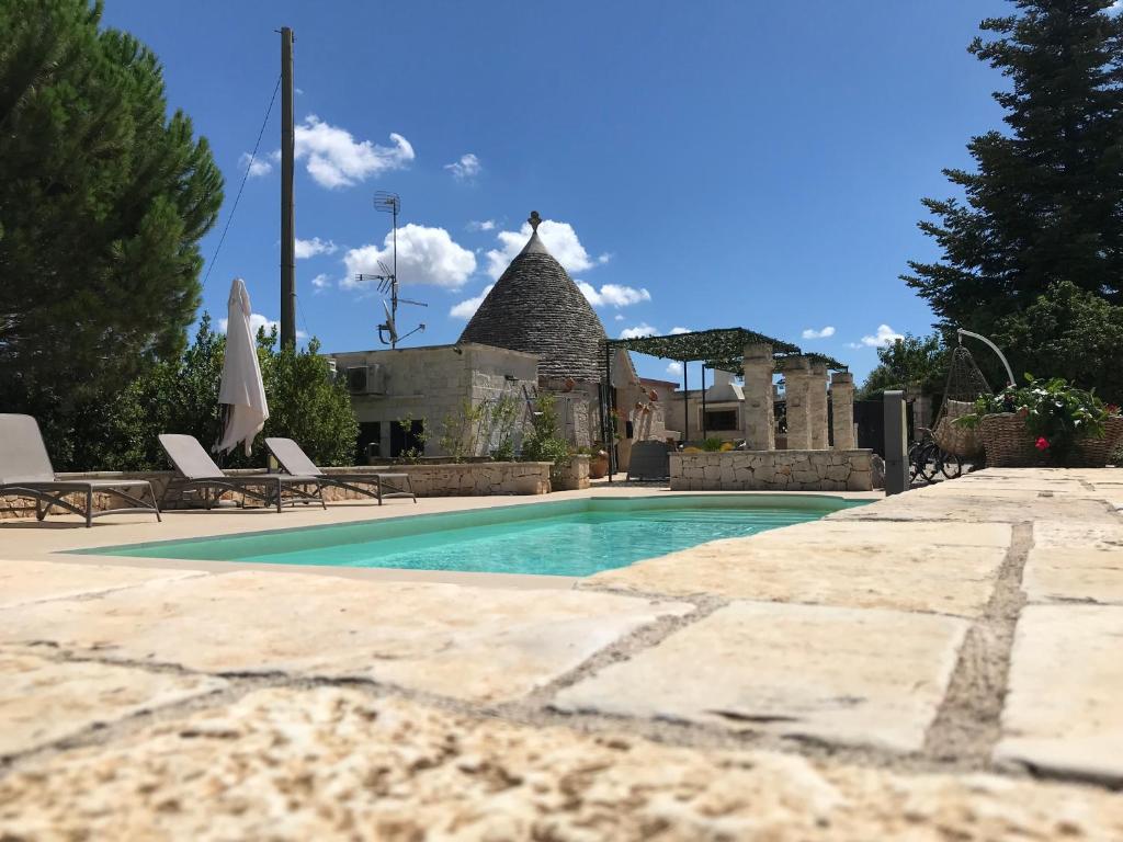 basen z 2 krzesłami i budynek w obiekcie Trullo Grace -Trulli Anti' Charme & Relax w Alberobello