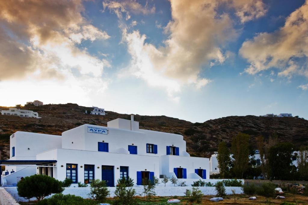 a white building with blue windows on a hill at Avra Pension in Ios Chora