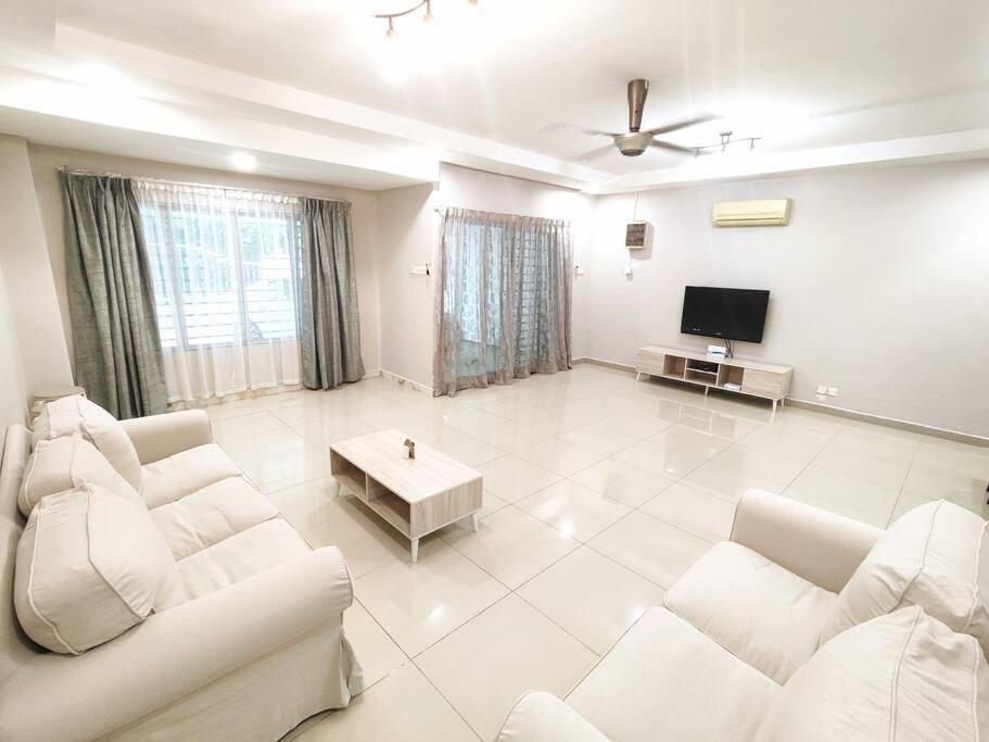 Puchong Landed Homestay - 2nd unit @ BKT Puchong في بوتشونغ: غرفة معيشة بأثاث أبيض وتلفزيون بشاشة مسطحة