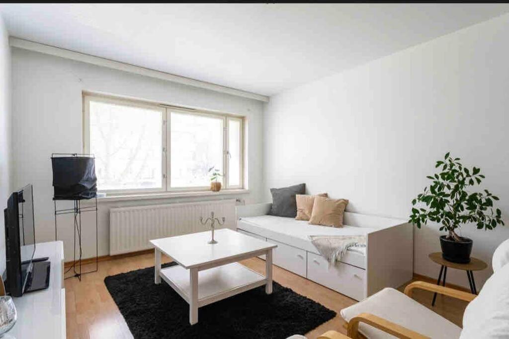 a living room with a white couch and a table at Kolmio Tampereen ydinkeskustassa in Tampere