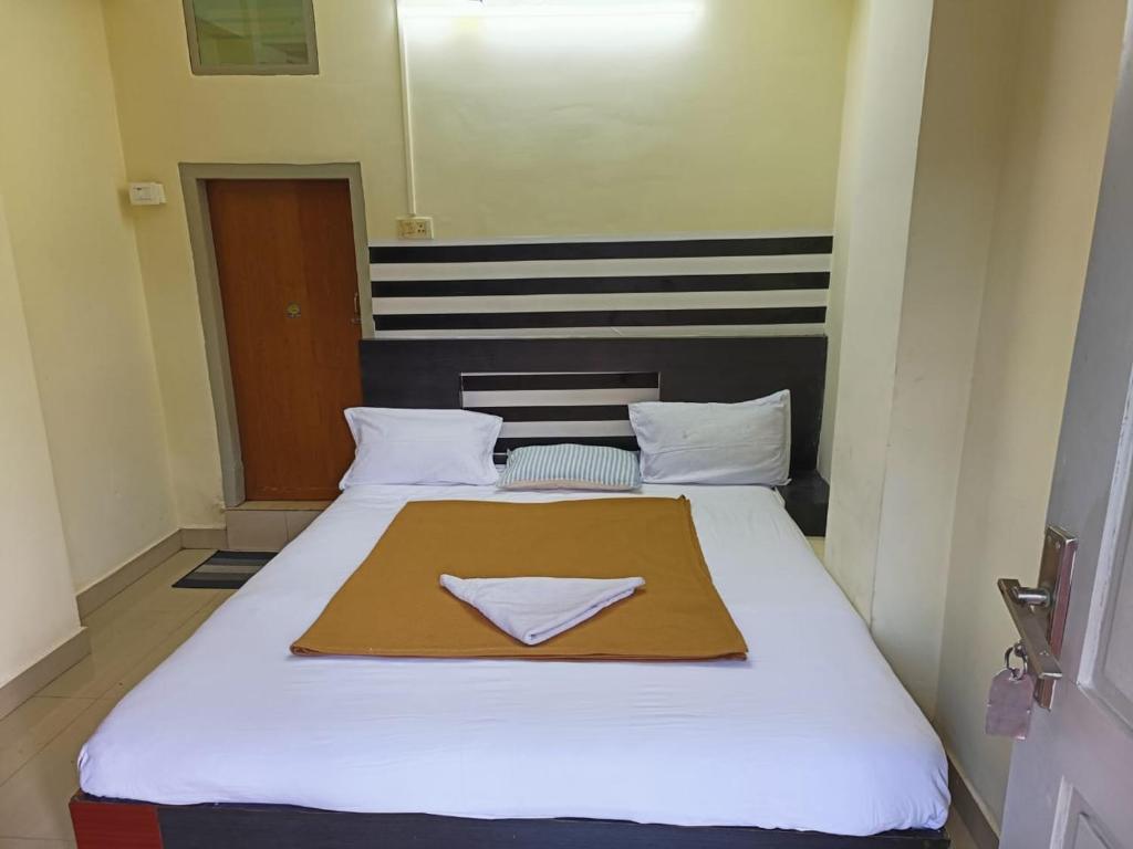 Un dormitorio con una gran cama blanca con una servilleta. en Hotel Orginal Residency, en Kollam