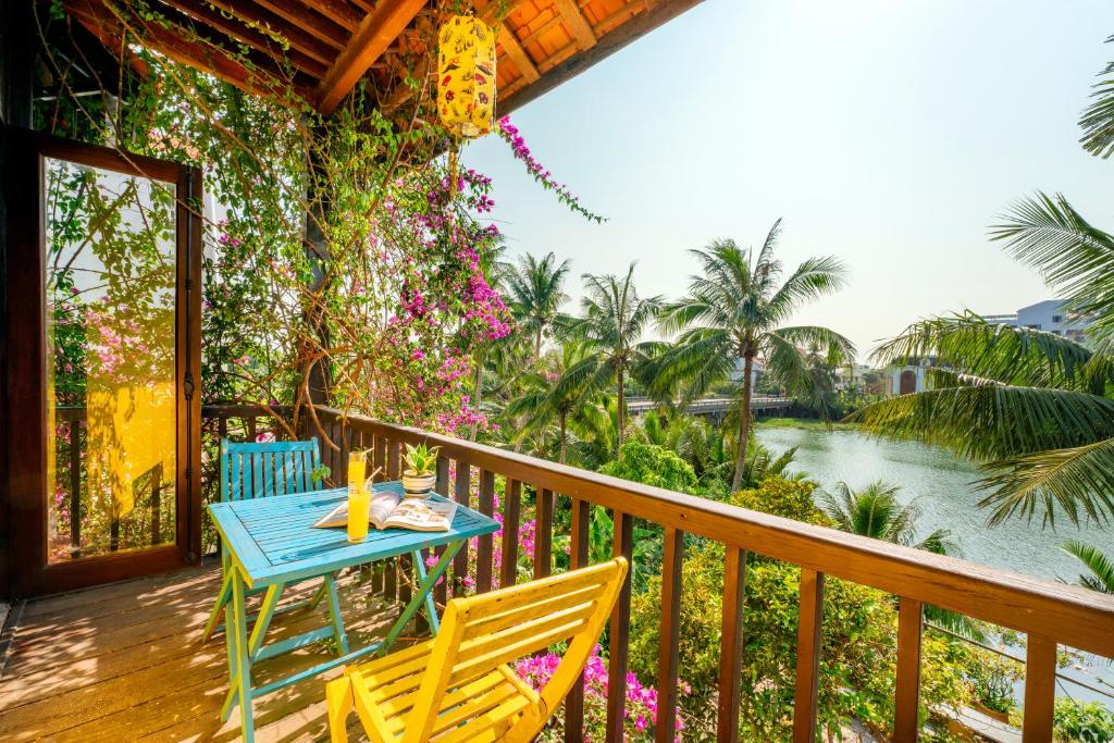 een tafel en stoelen op een terras met uitzicht op een rivier bij Hoi An Green Riverside Oasis Villa in Hội An