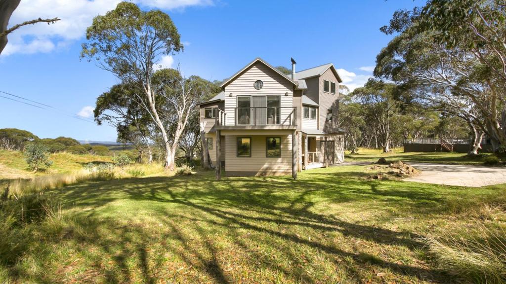 an old house on a grassy field with trees at Jasandre in Dinner Plain