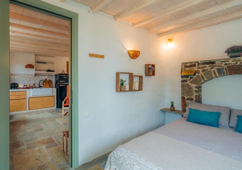 a bedroom with a bed and a kitchen in the background at Houses at Chrisopigi Sifnos in Chrisopigi