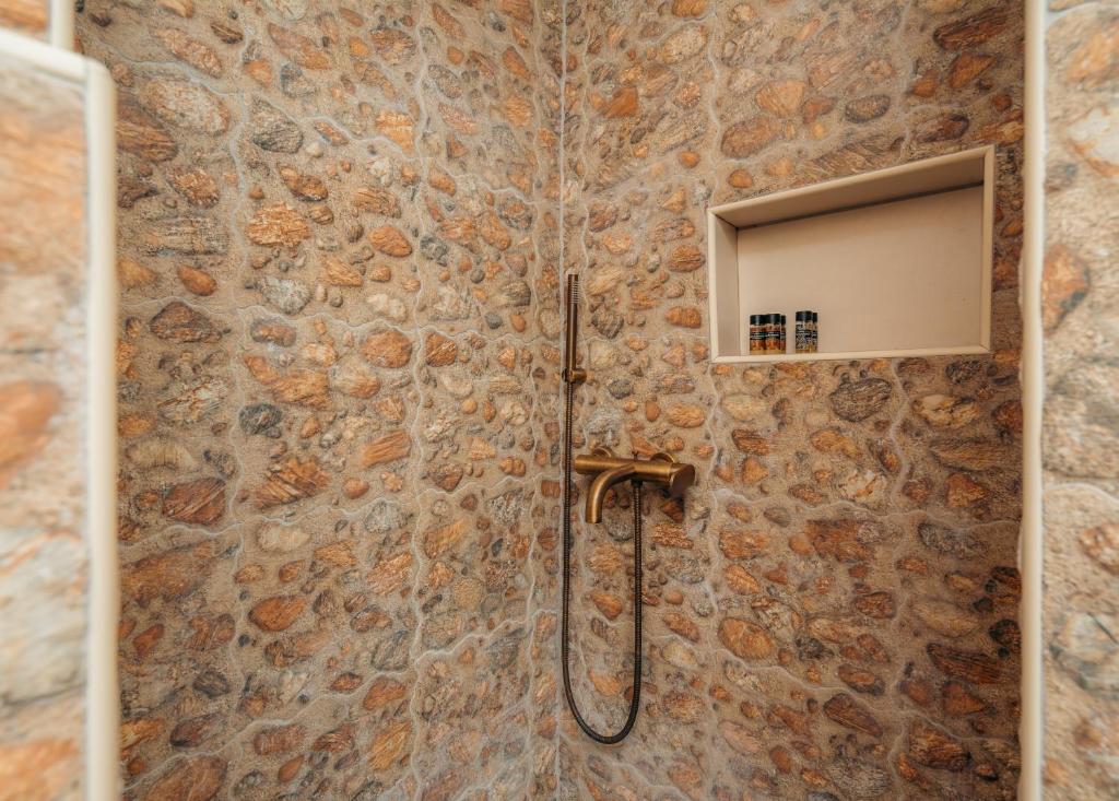 a bathroom with a shower with a stone wall at Houses at Chrisopigi Sifnos in Chrisopigi