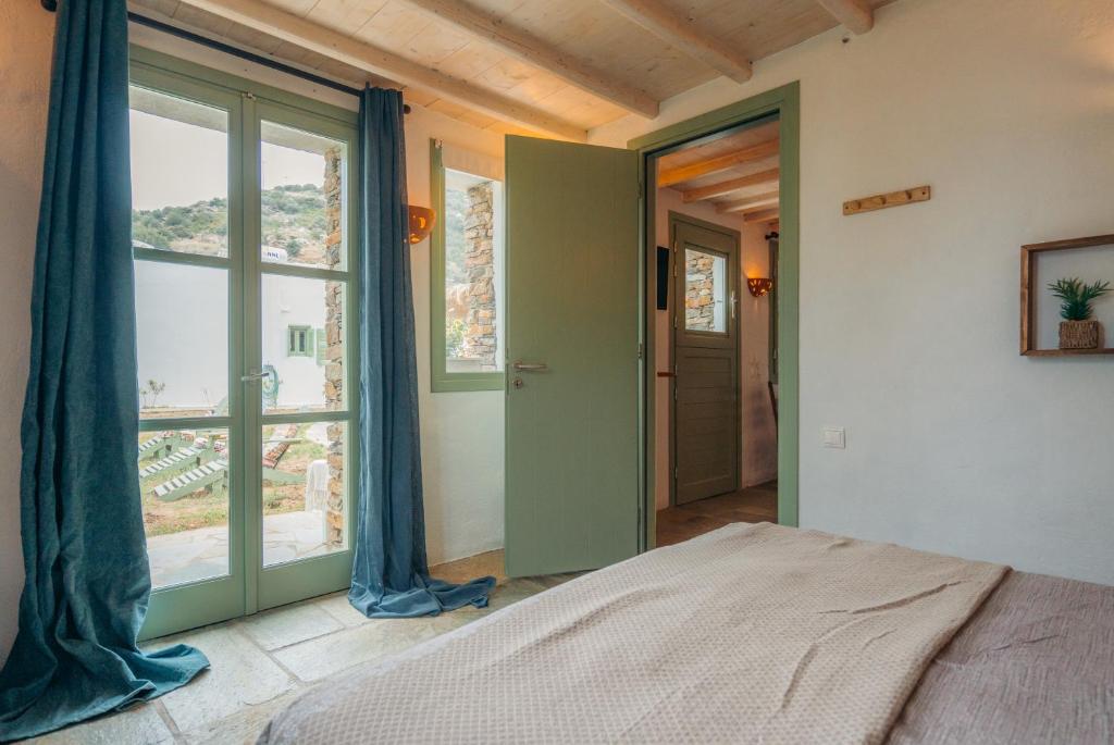 a bedroom with a bed and a large window at Houses at Chrisopigi Sifnos in Chrisopigi