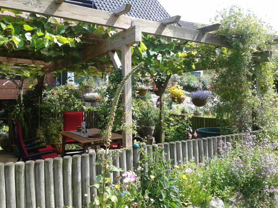 a wooden pergola with a table in a garden at Strand & Garten in Surendorf