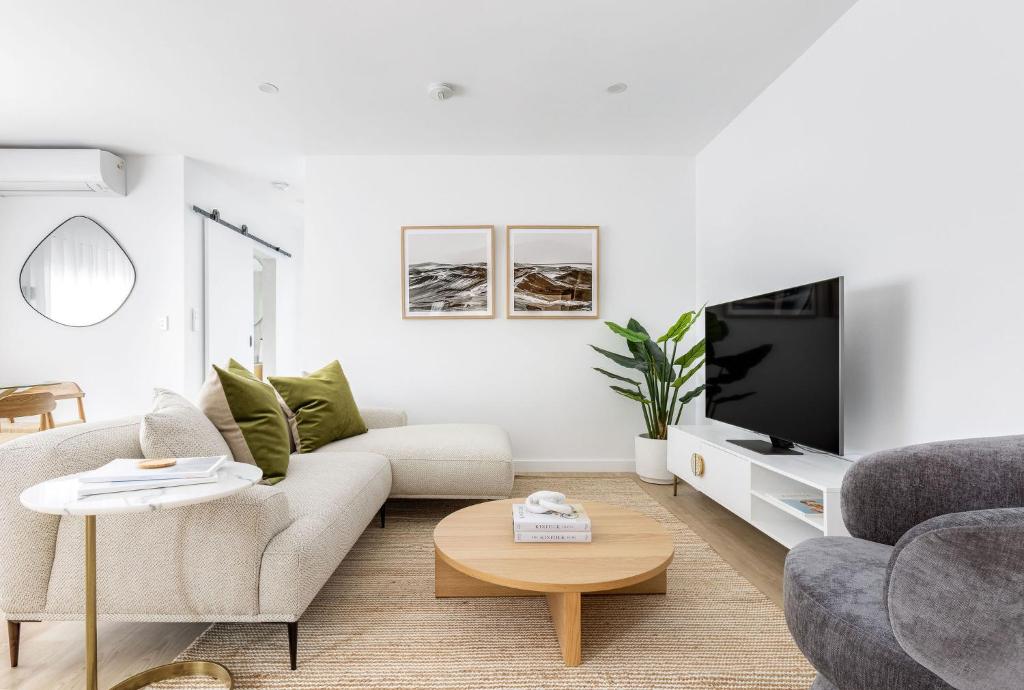 a white living room with a couch and a tv at Kahlo Bondi - Luxury Escape - 2 Bedroom Furnished Apartments in Sydney