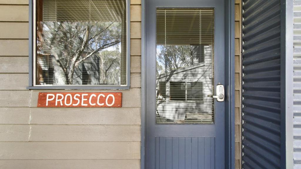 a door to a house with a processcolo sign on it at Prosecco in Dinner Plain