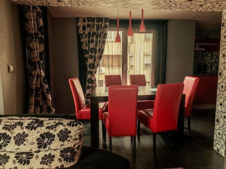 ein Esszimmer mit einem Tisch und roten Stühlen in der Unterkunft Aпартамент в близост до морето и центъра in Burgas City