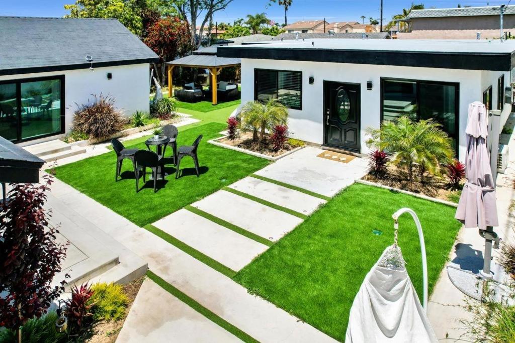 a garden with grass and chairs and a house at Pearl Beach Villa Huntington Beach in Huntington Beach