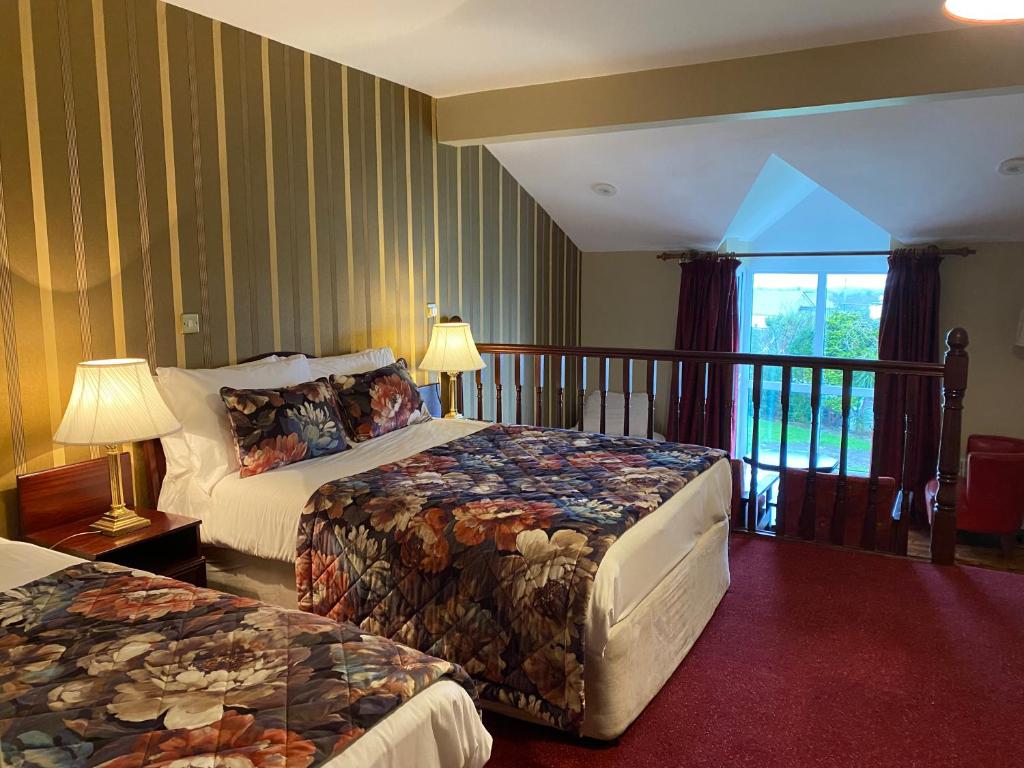 a hotel room with two beds and a balcony at Towers Hotel Glenbeigh in Glenbeigh