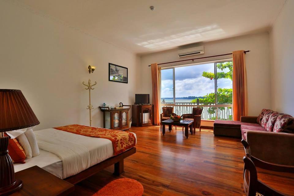 a bedroom with a bed and a living room with a window at Centauria Lake Resort in Embilipitiya