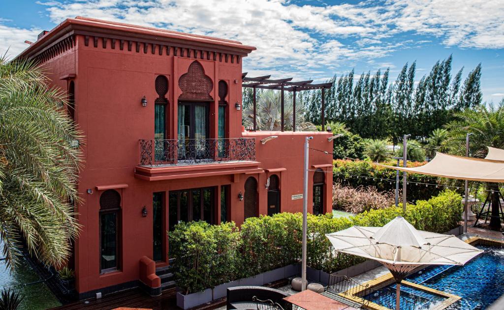 a red house with a balcony and a swimming pool at The Air Khaoyai Hotel SHA Extra Plus in Mu Si