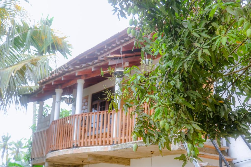 a house with a wooden balcony with trees at purple villa in Mirissa