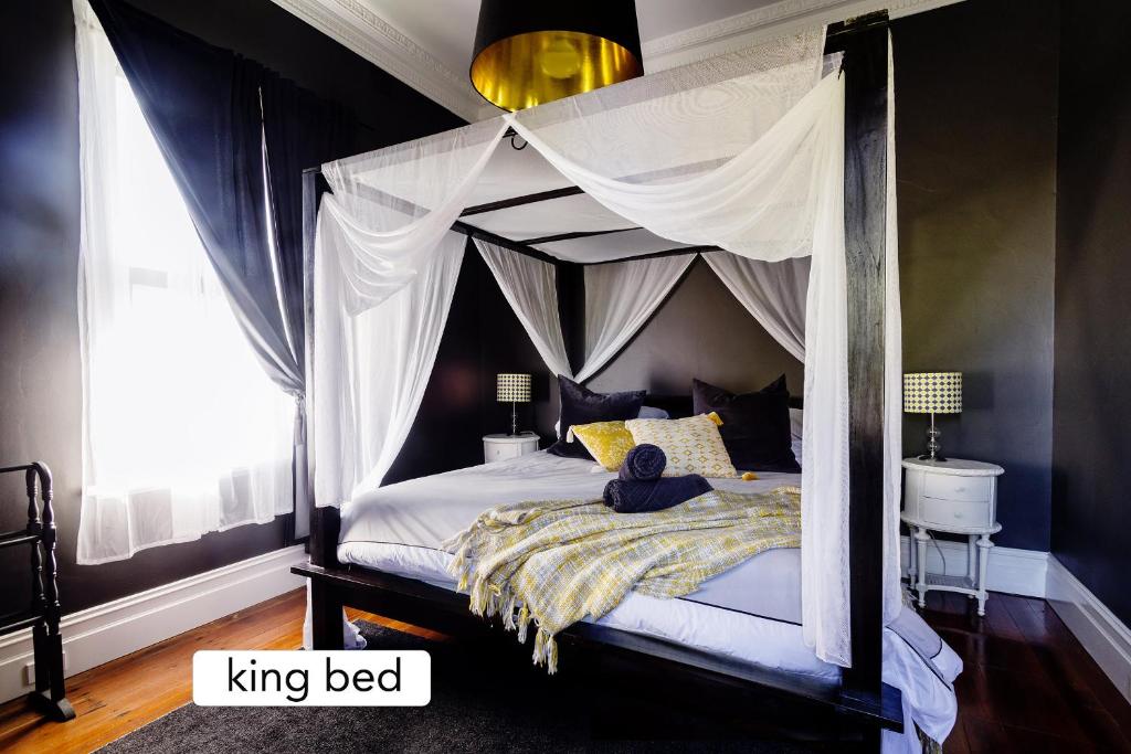 1 dormitorio con 1 cama extragrande con dosel en Piney Ridge, the Butler's Cottage 