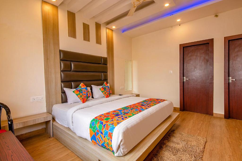 a bedroom with a large bed with colorful pillows at FabHotel AS Residency in Dehradun