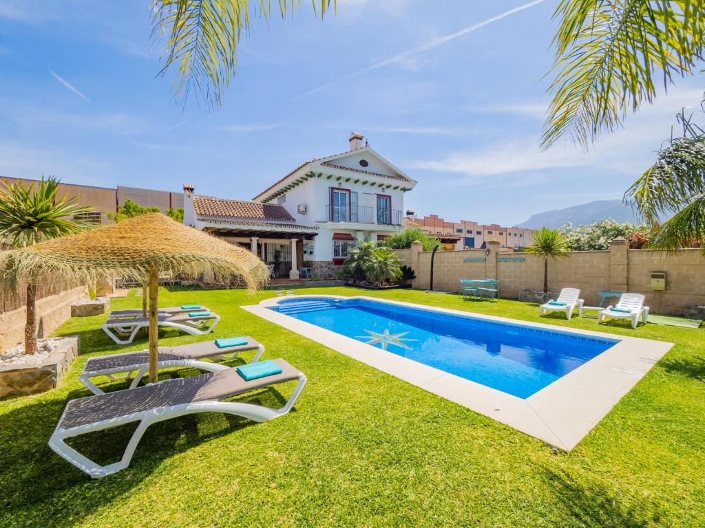 un patio trasero con piscina con sillas y sombrilla en Cubo's Villa La Quinta, en Alhaurín el Grande