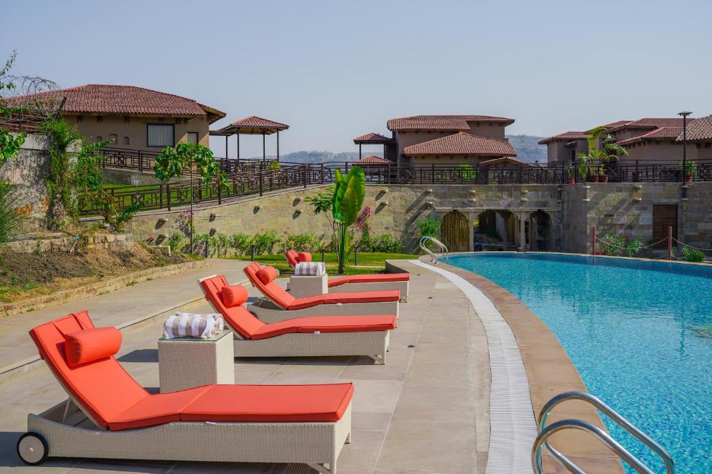 a row of lounge chairs next to a swimming pool at AamaGhati Wildlife Resort, Ranthambore in Sawāi Mādhopur