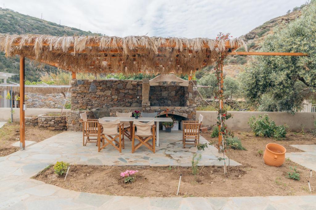 a patio with a table and chairs and a stone fireplace at Houses at Chrisopigi Sifnos in Chrisopigi