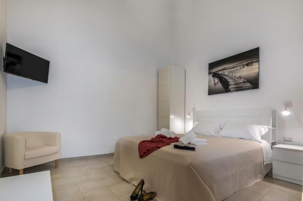 een slaapkamer met een bed, een stoel en een televisie bij De' Villanova House in Brindisi