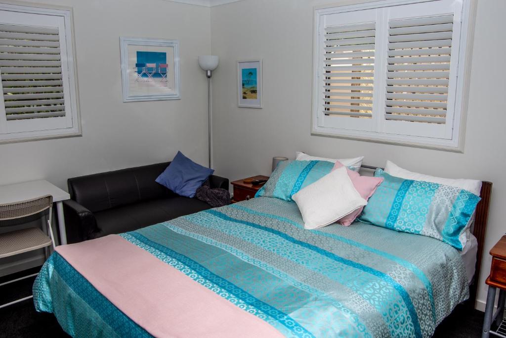 a bedroom with a bed and a couch and two windows at Macleay Island Getaway in Macleay Island