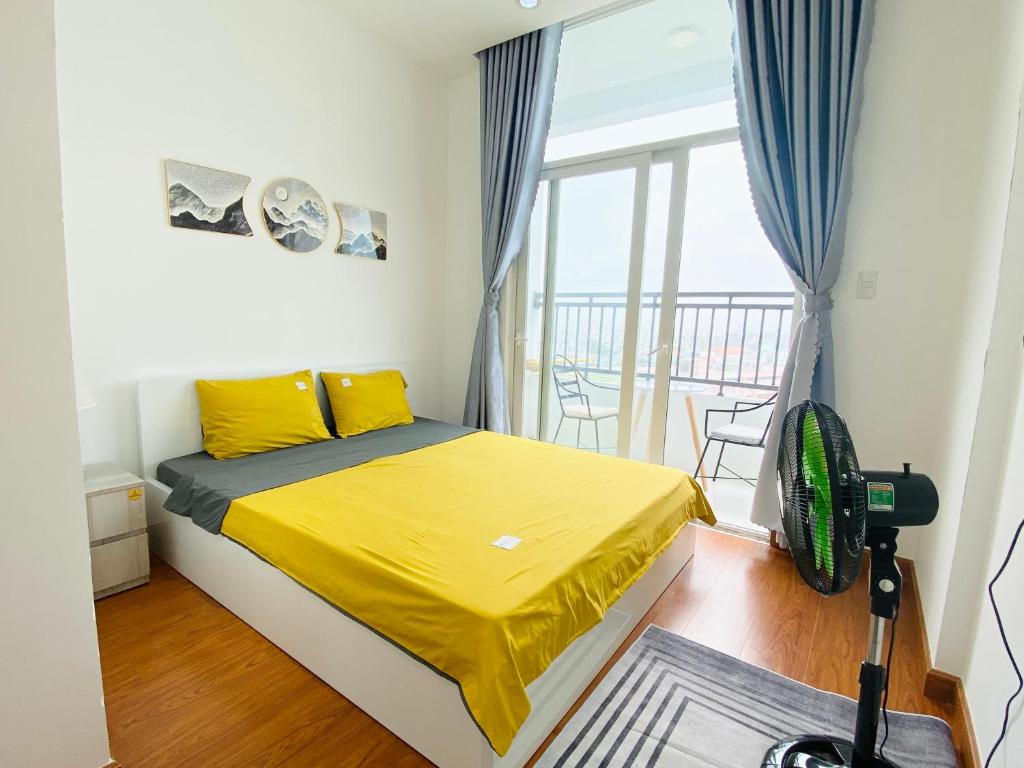 1 dormitorio con 1 cama con sábanas amarillas y balcón en Alpha Homestay Marina Long Xuyên en Ấp Ðông An (1)