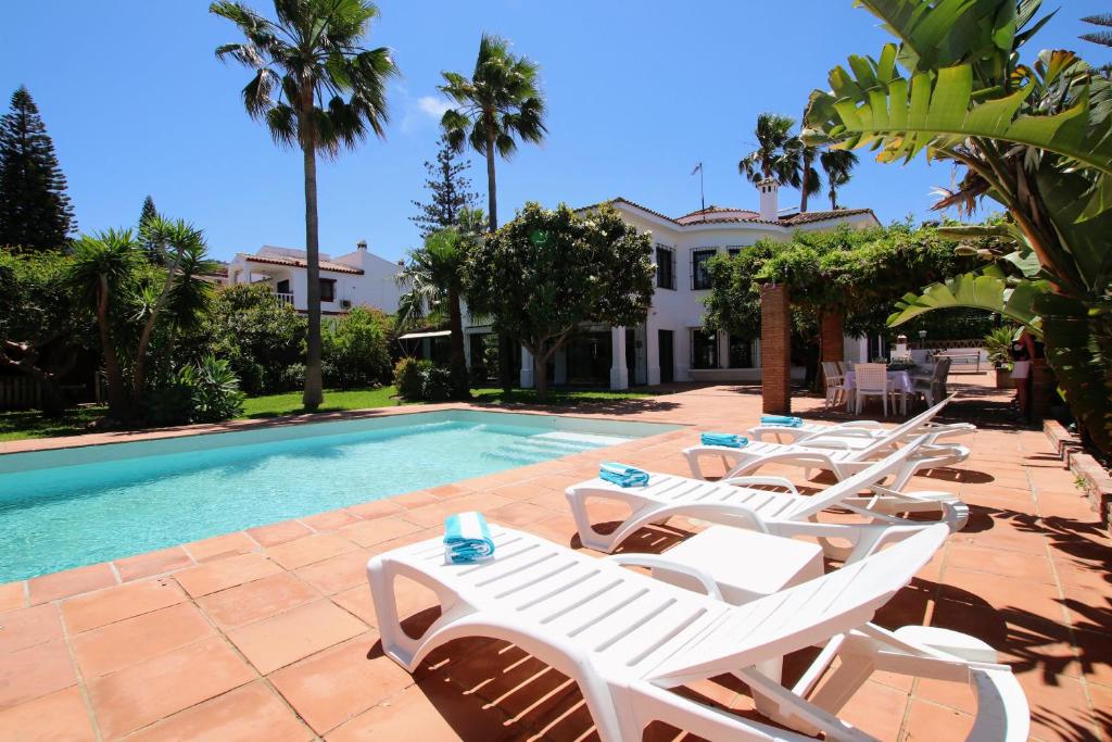 a group of white lounge chairs next to a swimming pool at TESS Villa Los Monteros in Alhaurín de la Torre