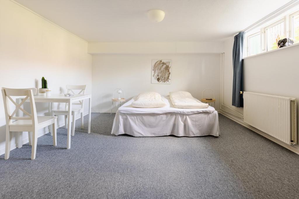 een witte slaapkamer met een bed en een tafel bij Værelse i rolig villakvarter, central beliggenhed in Odense