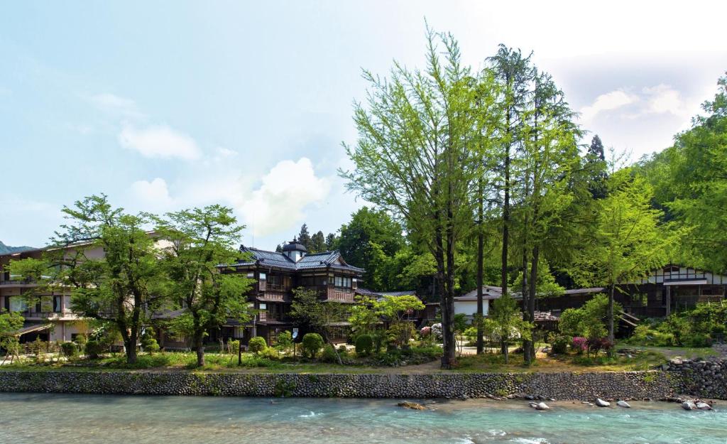 a house next to a river with trees at Rankeisou in Sanjo