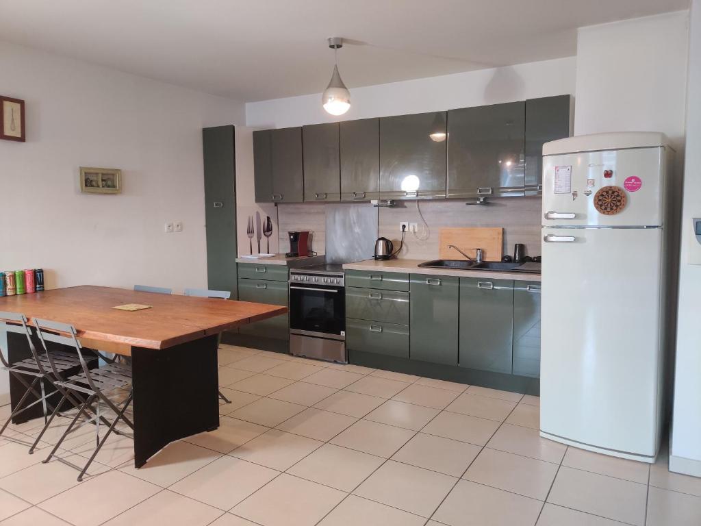 une cuisine avec une table en bois et un réfrigérateur blanc dans l'établissement Le Village 76 m2 Climatisation 1er arrondissement gare à pied, à Marseille