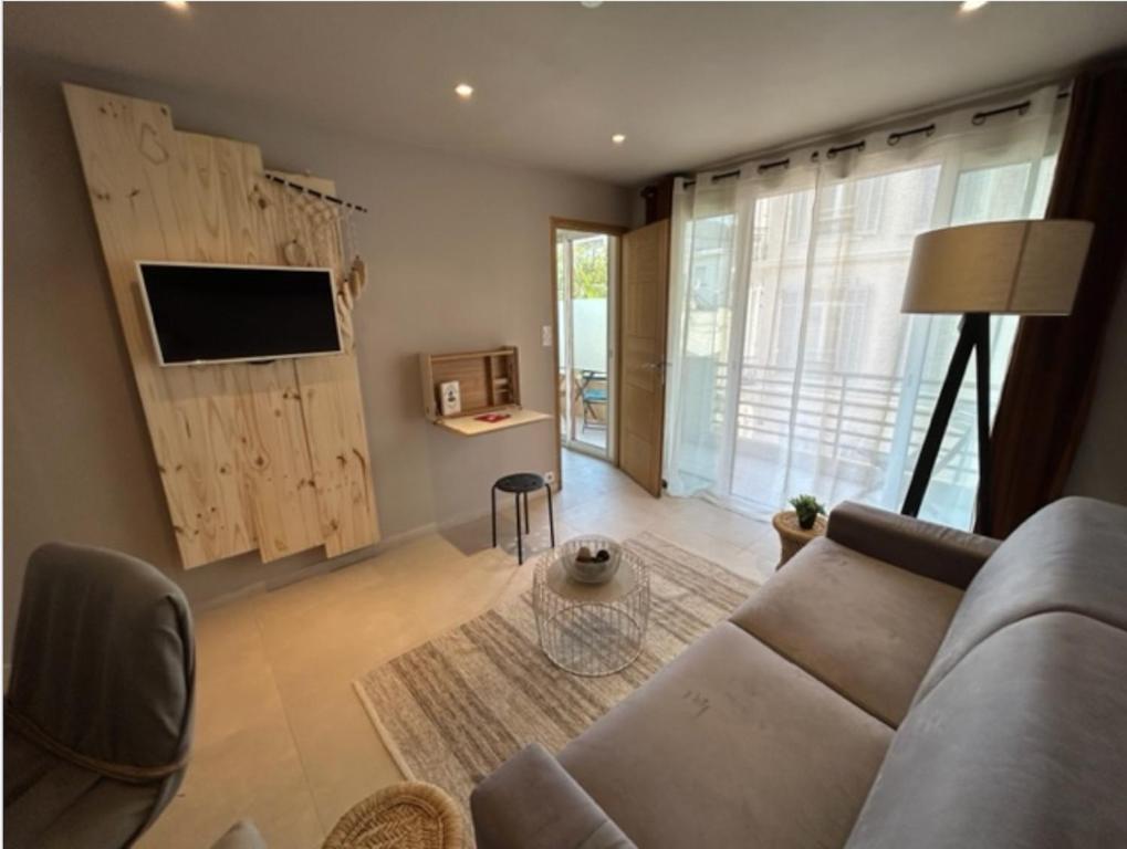 uma sala de estar com um sofá e uma televisão em Le Bristol em Cannes
