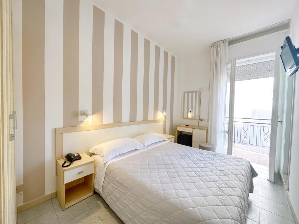 a bedroom with a bed with a striped wall at Aura Living Hotel in Rimini