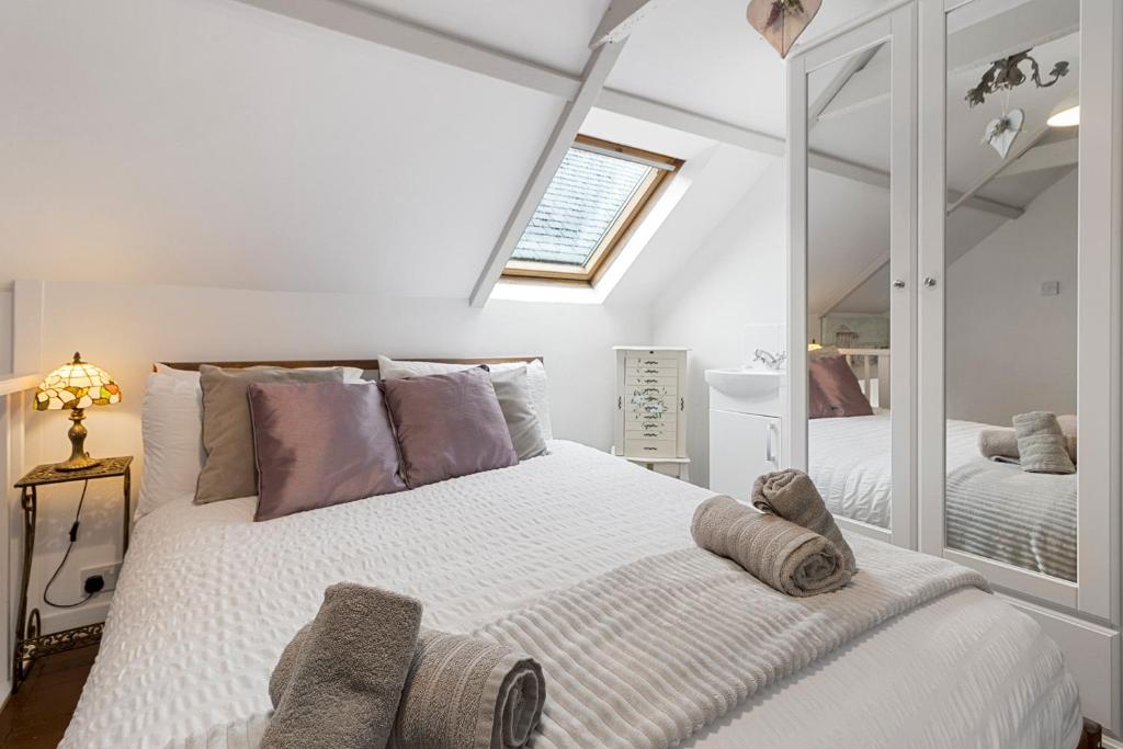 een slaapkamer met een groot wit bed met paarse kussens bij Pip's Cottage by Staytor Accommodation in Exeter