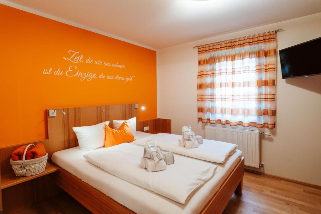 2 Einzelbetten in einem Zimmer mit orangefarbenen Wänden in der Unterkunft Burgls Apartmenthaus in Tröpolach