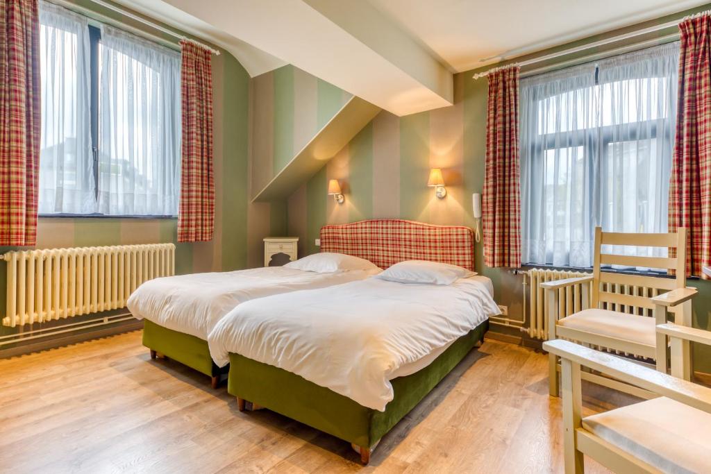聖胡伯特的住宿－Hôtel Le Cor de Chasse，一间卧室设有两张床和两个窗户。