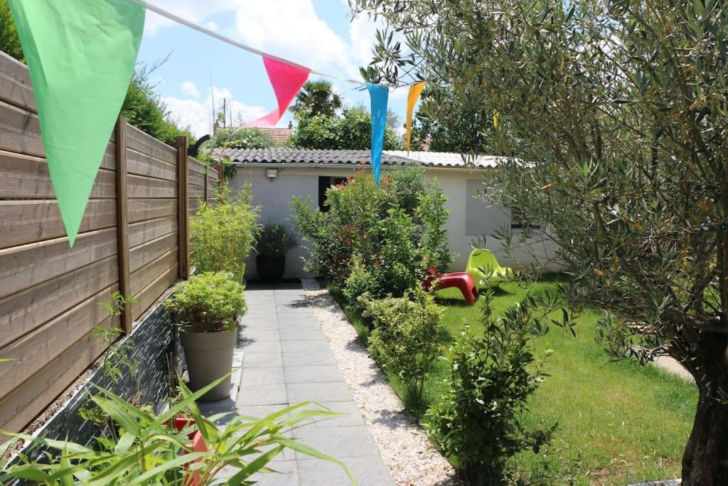 einen Hinterhof mit einem Zaun und einem Garten mit Flaggen in der Unterkunft Détente assurée dans ce logement avec balnéo in Rezé