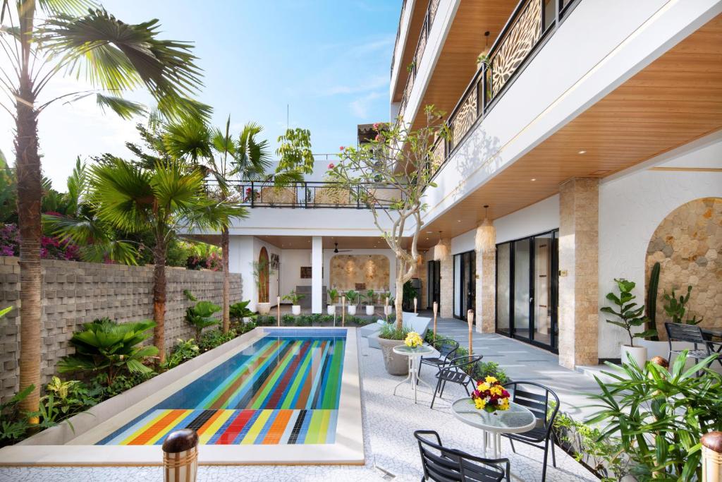 a pool in the middle of a courtyard with tables and chairs at Amandaya Canggu in Canggu