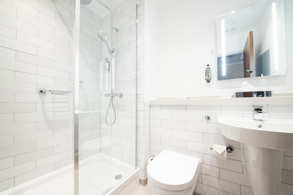 a white bathroom with a shower and a toilet and a sink at Miller & Carter Sheffield by Innkeeper's Collection in Sheffield