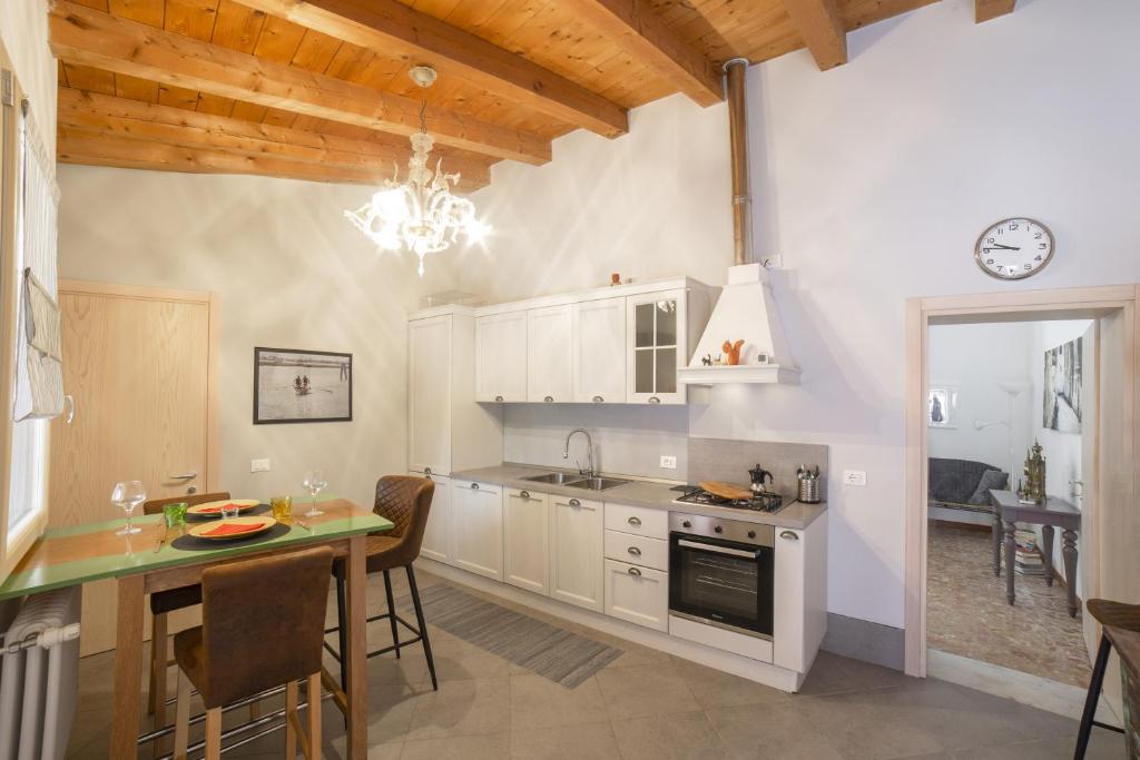 a kitchen with white cabinets and a table and a counter at Ca' de la Gondola, Murano in Venice