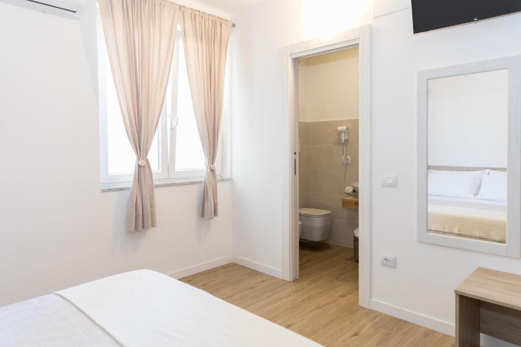ein Schlafzimmer mit einem Bett und einem Fenster sowie ein Badezimmer in der Unterkunft B&B Dal Maestro in Maratea
