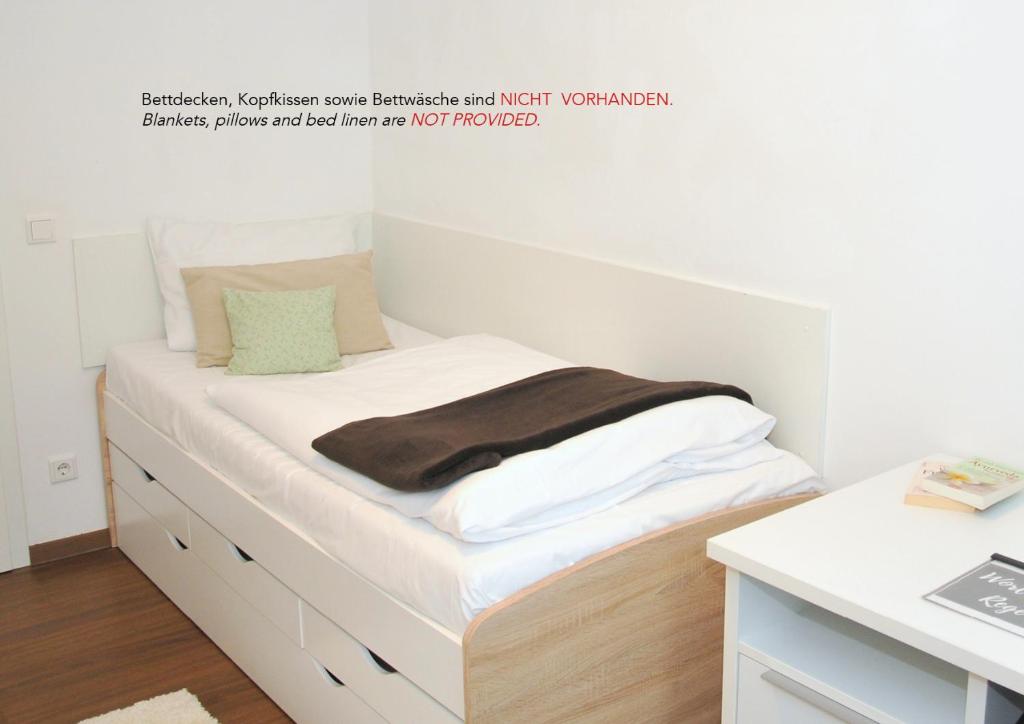 um quarto com uma cama com lençóis brancos e uma secretária em WG Zimmer in der World of Living K em Regensburg
