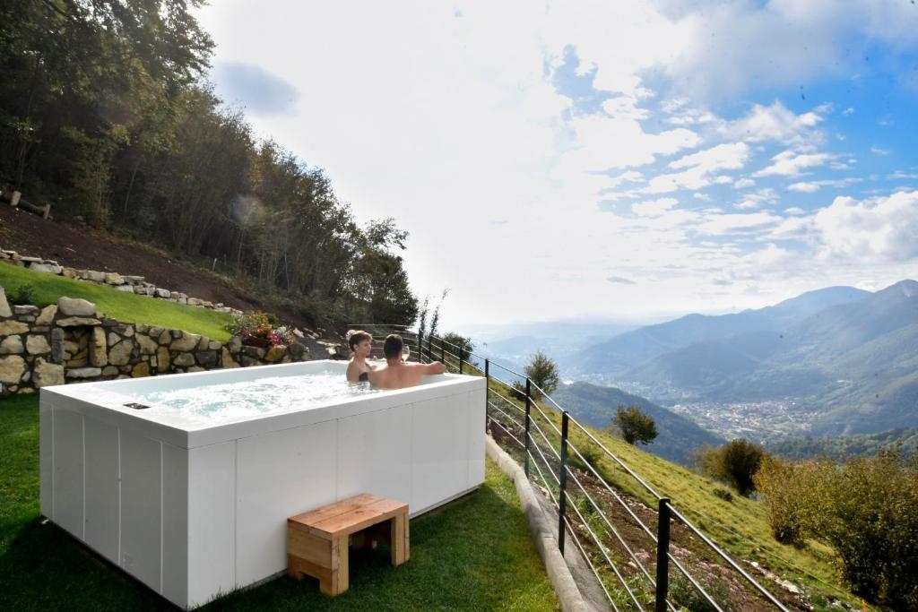 two people in a hot tub with a view of mountains at Narciso Home in Adrara San Rocco