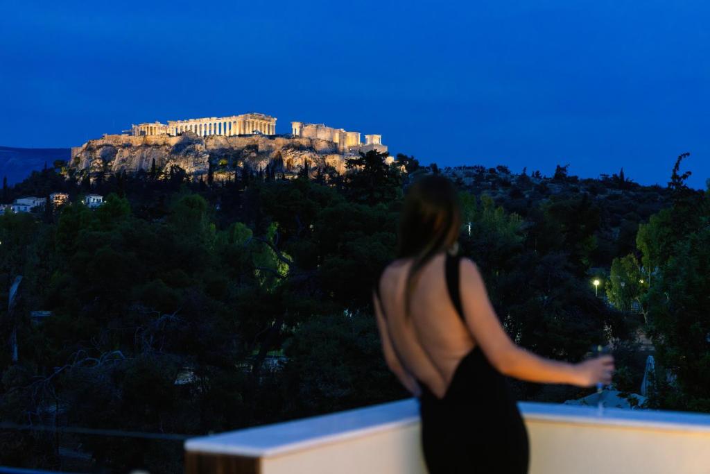 a woman standing on a ledge looking at thehens at Visum Acropol ,3BR - Private Terrace-Jacuzzi - Amazing View in Athens